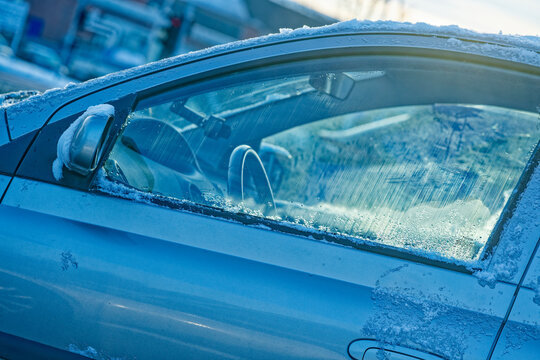 Frozen car window with ice and snow on a cold winter day outdoors