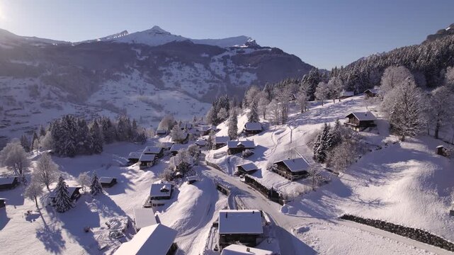 Aerial view of snow covered alpine village in Swiss mountains during winter sunrise