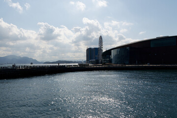 Fototapeta premium Panoramic coastal view of Shimonoseki Kaikyokan Aquarium and Ferris wheel with bright sun reflecting on the sea waves.