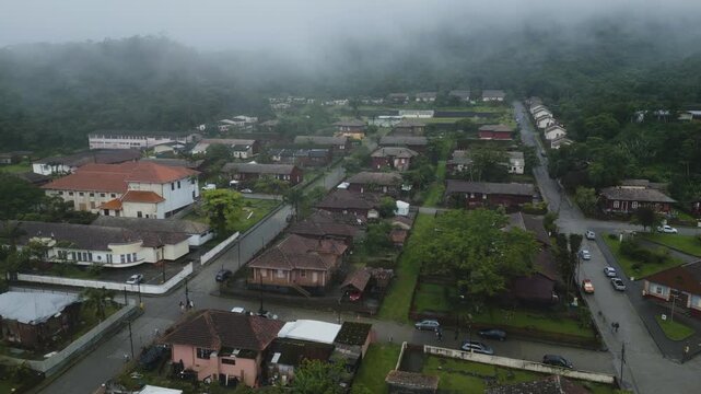 Dramatic aerial footage of historic Paranapiacaba village shrouded in thick fog, nestled in lush Atlantic Forest mountains near Santo Andre, Brazil.