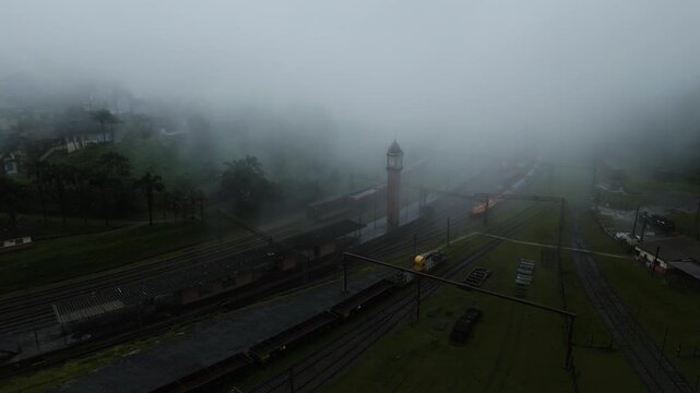 Atmospheric drone footage capturing misty morning fog enveloping historic railway station and vintage train cars in Paranapiacaba district, Santo Andr&eacute;, S&atilde;o Paulo, Brazil.
