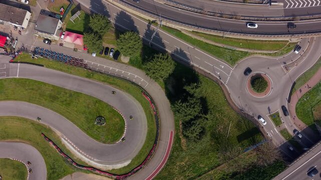 Drone view above a karting circuit with multiple racers. Tight turns and fast laps highlight competitive racing atmosphere and precision driving on asphalt track.