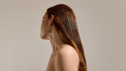 Fototapeta premium Woman with long hair after treatment on neutral background. Concept of smooth hair result, care routine outcome, healthy appearance and beauty maintenance.