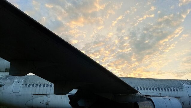 Close-up view of a weathered airplane fuselage and engine under a dramatic cloudy sky