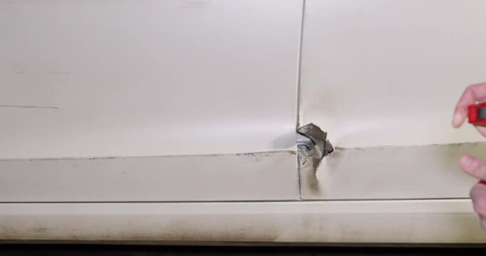 Man hands hold tape measure testing hole on car door at service station closeup. Insurance inspector analyzes crash evidences on vehicle in professional garage