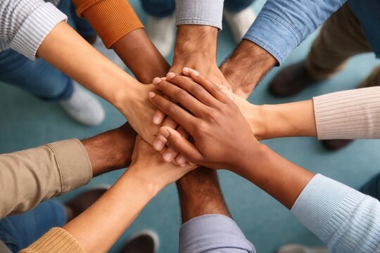 Diverse group of people putting hands together in a circle demonstrating unity