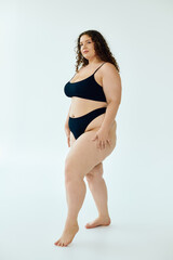 Fototapeta premium Curly plus size woman confidently celebrating her beauty in a studio setting