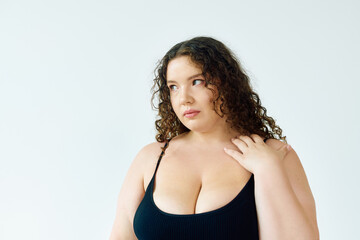 Fototapeta premium Celebrating curves in a bright studio: A young woman embraces her beauty