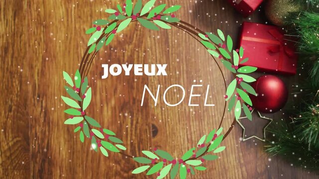 Animation of joyeux noel text over christmas decorations on wooden background