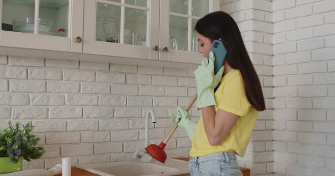 Phone call from woman to plumber about broken sink problem in home kitchen, girl in rubber gloves using plunger to unclog sewer drain, clear blockage. Customer calling emergency plumbing service