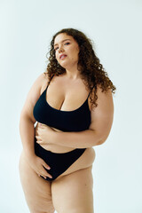 Fototapeta premium Curvy young woman proudly flaunting her beauty in chic underwear in studio