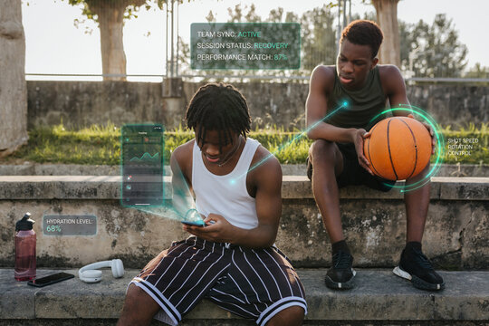Two athletes reviewing basketball performance data on smartphone during outdoor training break