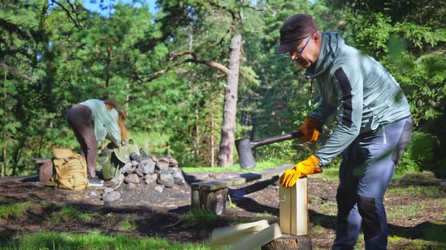 Active man preparing firewood at designated national park campfire site. Sustainable outdoor lifestyle, responsible tourism and forest management concept in sunny Finland nature.