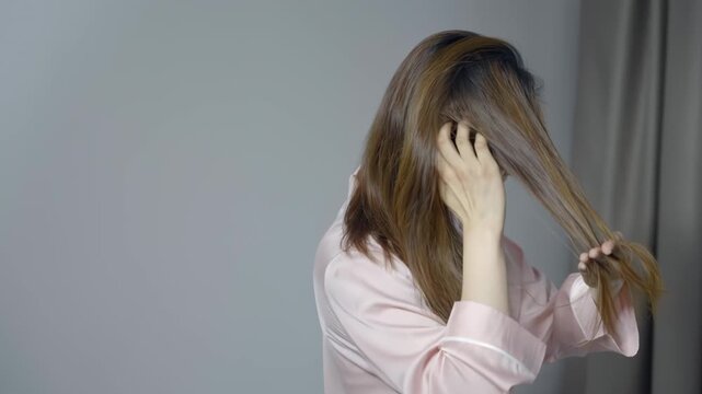 Frustrated young girl woman female long hair, difficulty brushing her tangled hair, feeling dissatisfied with tangles, dryness, frizz or split ends, thinking of spa professional treatment procedures