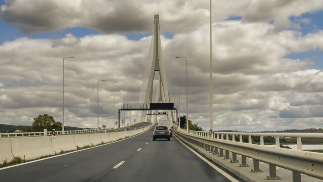 Dramatic perspective of the tall white bridge pylon and cables rising above the motorway over the Guadiana River.