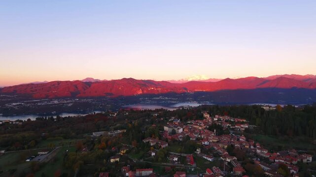 Aerial view of Pella village and Lake Orta at sunset, with mountains reflecting warm light