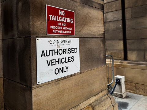 Authorised vehicles only sign and no tailgating warning on sandstone building entrance in Edinburgh, Scotland, UK