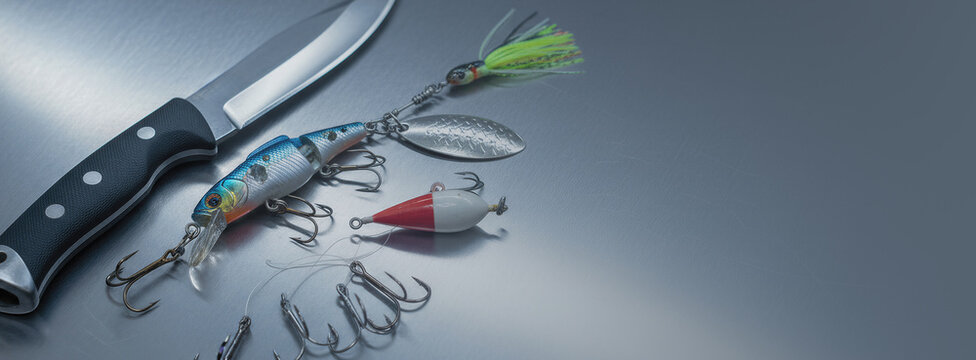 Fishing knife and colorful artificial lure with metal hook on stainless steel table. Tackle for angling adventure. Equipment for fisherman to catch fish in river or lake outdoor hobby. Banner with