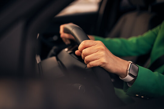 Woman driving a car wearing smartwatch and green jacket