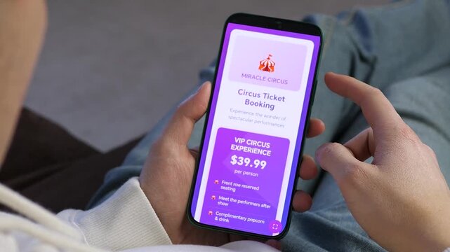 Hands holding smartphone with an event booking app. User viewing circus ticket options and VIP offers on a colorful mobile interface. Concept of online entertainment reservation and digital ticketing