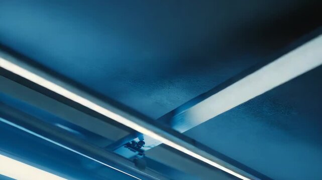 Glowing fluorescent lamp providing bright cool blue light, creating an abstract and futuristic atmosphere in a dark environment with visible ceiling fixtures