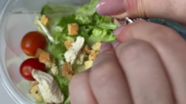 tearing apart a foil packet of salad dressing for home delivery of Caesar salad