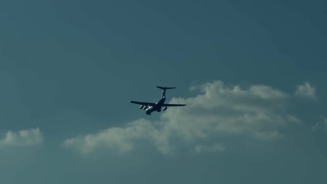 Russian Ilyushin Il-76 strategic airlifter flying in a cloudy blue sky. Military transport aircraft in mid-flight. Heavy cargo jet plane for aviation, defense, and global logistics industries.