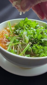 Chef garnishing encebollado con yuca traditional ecuadorian soup. squeeze lemon juice into pho bo soup, a traditional Vietnamese soup.