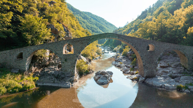 Devils Bridge aerial view Rhodope mountains Bulgaria summer landscape. Ancient stone architecture Arda river water landmark. Drone shot historic bridge Balkan mountains travel photography scenery view