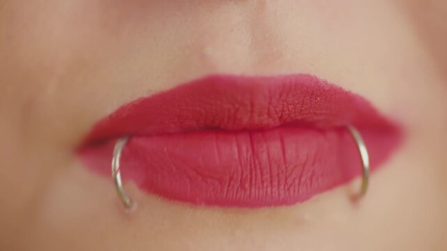 Woman's mouth with red lipstick and lip piercing talking