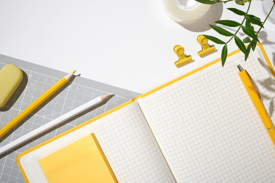 Top view of yellow office stationery with an open notebook, pen, and pencils. Copy space.