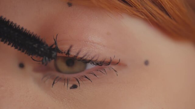 Woman applying black mascara on eyelashes