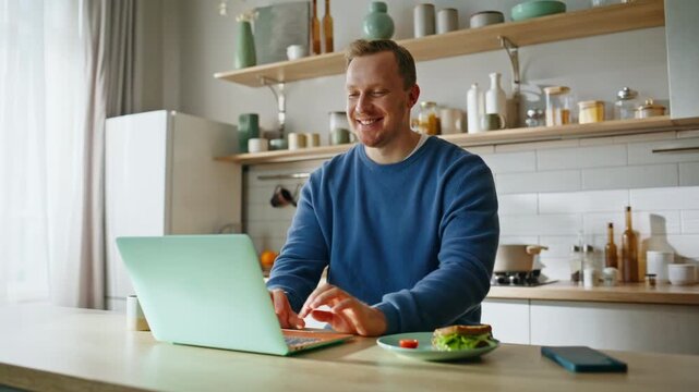 Smiling man video calling sitting kitchen countertop at home breakfast closeup. 