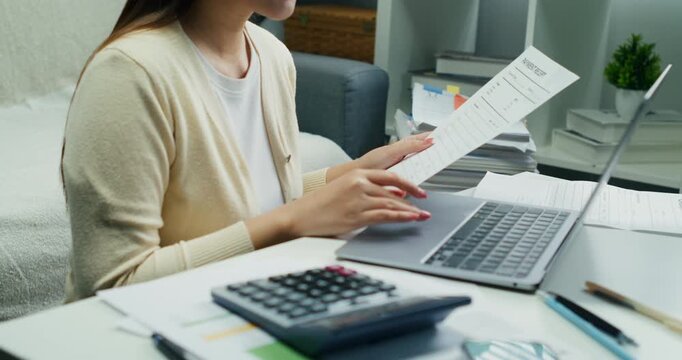 A professional woman ensuring connectivity with a client. She is reviewing digital commerce documents and processing an online bill payment via laptop.