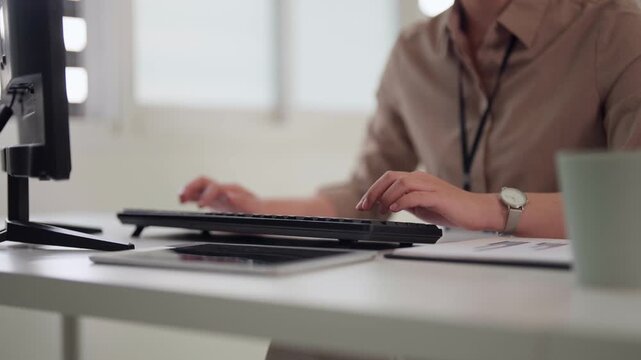 Adult Asian woman works focused on computer in bright modern office professional workspace productivity business concept technology corporate employee remote work solution