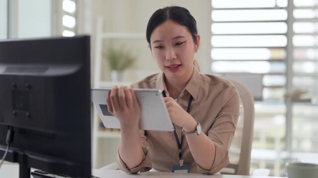Asian adult businesswoman professional working focused typing data entry online report research computer office modern workspace productivity corporate management