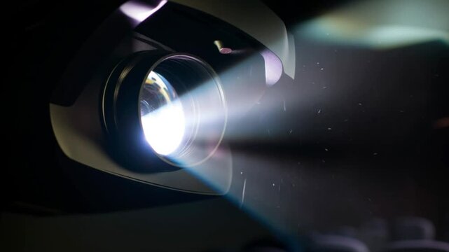 Projector lens emitting bright light beam in dark room, modern multimedia presentation device with cinematic optical projection, technology display equipment, digital visual communication footage
