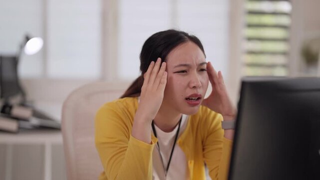 Asian adult woman professional feels intense work stress headache problem facing computer screen at home office workspace pressure