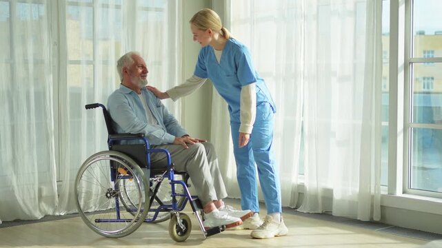 Help support retirement healthcare. Nurse helping old man in wheelchair. Patient and woman in nursing home for medical caregiver. Nurse taking care of paralyzed man in chair for people with disability