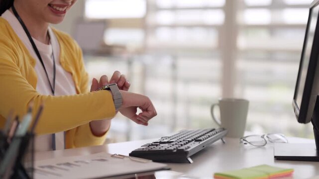 Adult Asian woman checking smartwatch in modern office workplace worker managing time productivity business schedule efficiency professional environment
