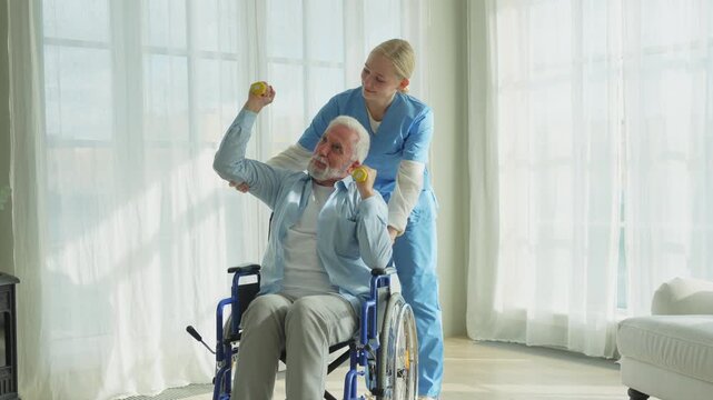Support rehabilitation healthcare. Nurse helps old man patient in wheelchair picking up dumbbells. Paralyzed man in chair for people with disability doing sports exercise with nurse. Medical caregiver