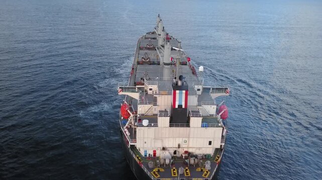 Rear deck of bulk carrier ship heading towards open sea. Bulkers are merchant ships, specially designed to transport unpackaged bulk cargo, such as grains, metal ores, timber, sand or coal