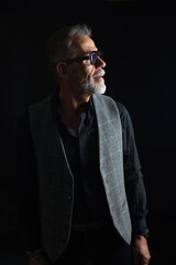 Fototapeta premium side view of portrait of a mature man looking up on black background