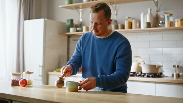 Man filling coffee cup holding coffeepot at modern kitchen interior closeup. 
