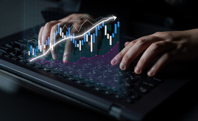 Fototapeta premium Detailed image showcasing hands typing on a laptop, enhanced by a stock market graph overlay indicating financial analysis and business growth in a professional setting. Impute