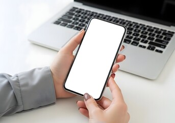 Obraz premium Close up view of a persons hands holding a smartphone in front of a laptop computer