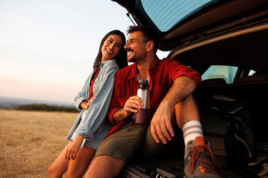 Couple going for summertime road trip taking a break on a mountain viewpoint