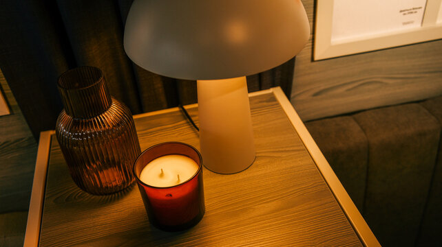 Cozy bedside table with a lit candle, decorative vase, and modern lamp