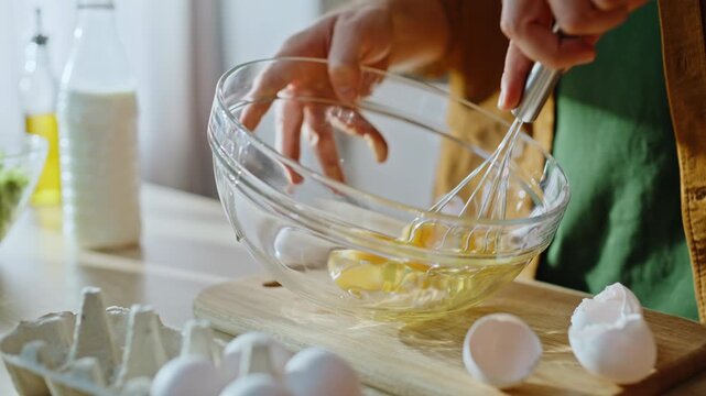 Man hands whisking eggs in glass bowl preparing omelette home kitchen closeup.