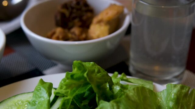 Sweet sticky rice with raisins generous amount of creamy peanut sauce being poured from a spoon over a bowl of Gado-gado.